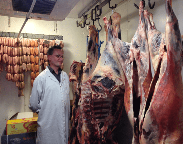 Billy in the walk-in-fridge standing next to hanging hoggets